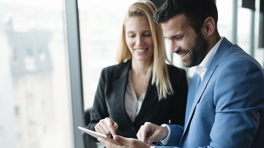 a diverse couple of top level execs seem happy with what they see on the screen of a tablet